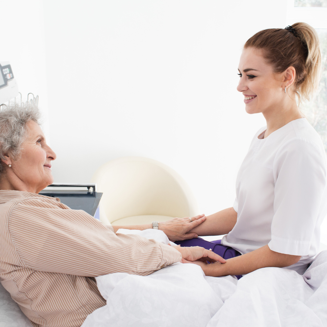 A nurse is talking to an elderly woman in a hospital bed