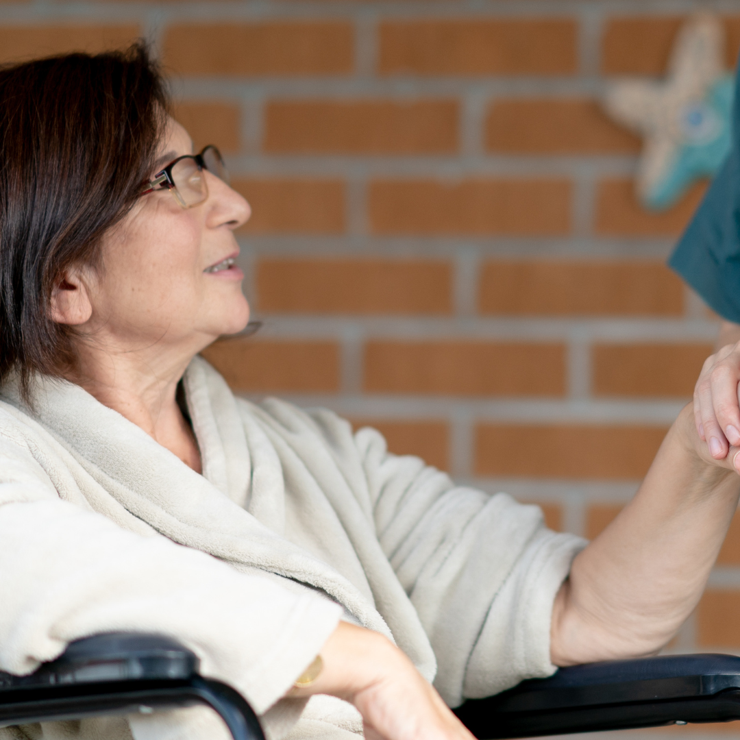 A woman in a wheelchair is shaking hands with another woman.