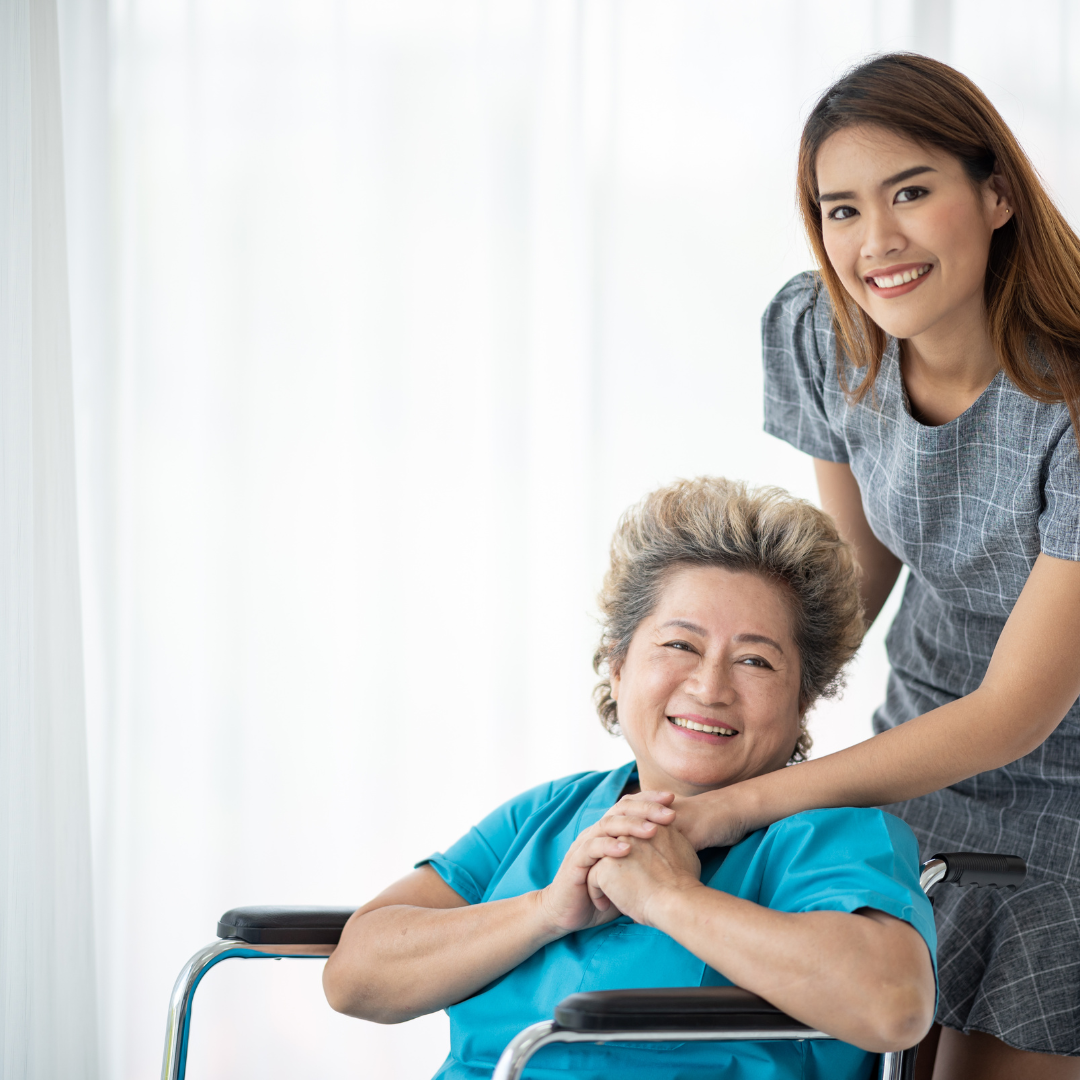 A woman is sitting next to an older woman in a wheelchair.