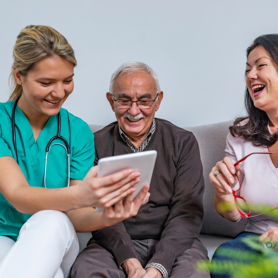 A group of people are sitting on a couch looking at a tablet.