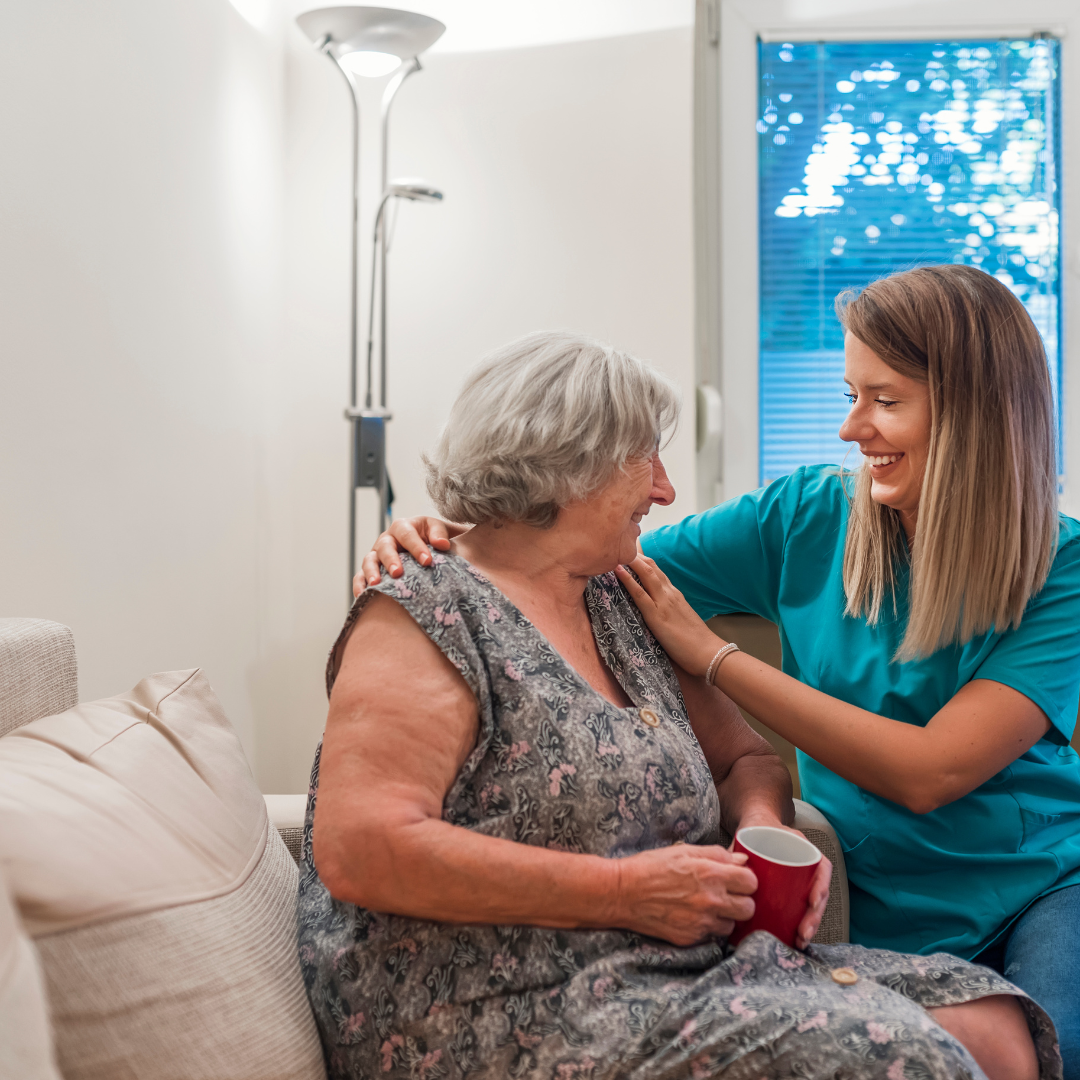 An elderly woman is sitting on a couch with a nurse.