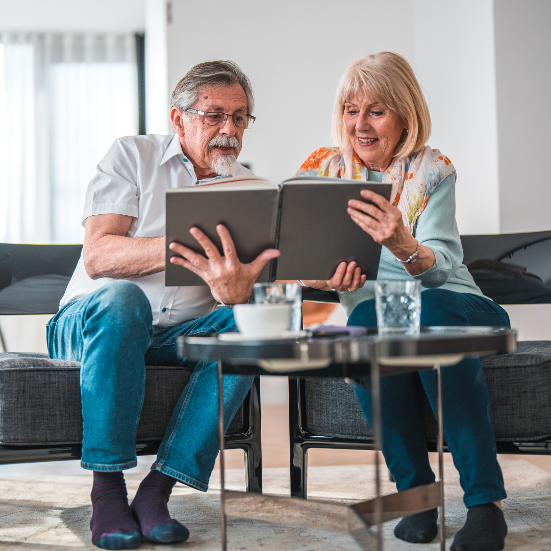 A man and a woman are sitting on a couch looking at a tablet.