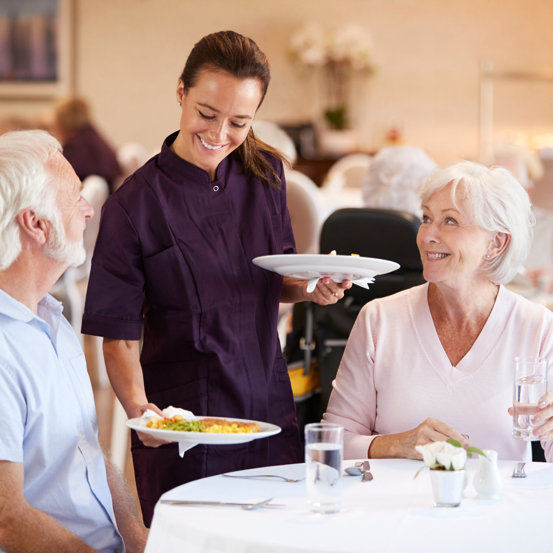 A woman is serving food to a man and woman at a table.