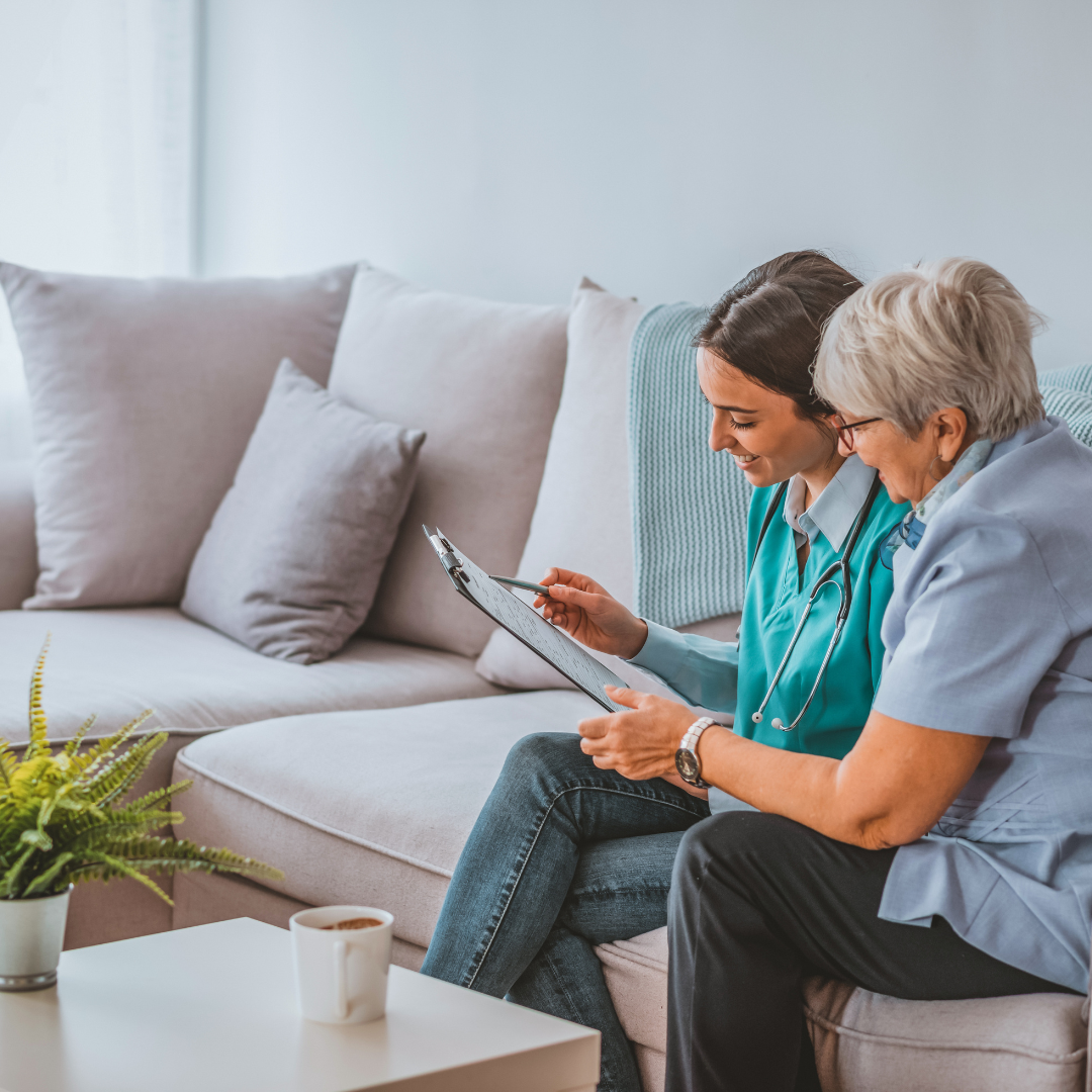 Two women are sitting on a couch looking at a tablet.