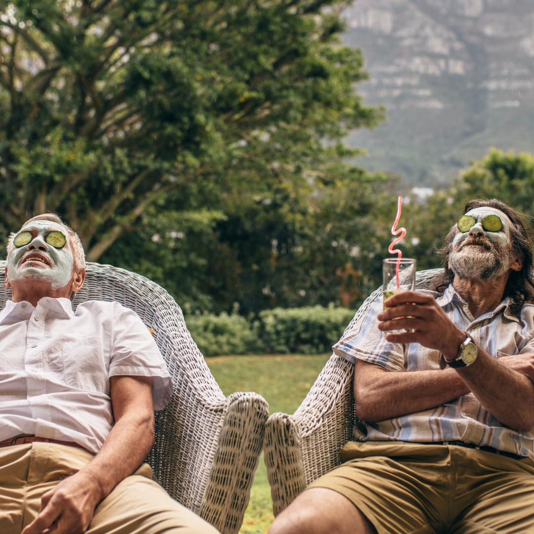 Two men wearing face masks are sitting in chairs drinking wine