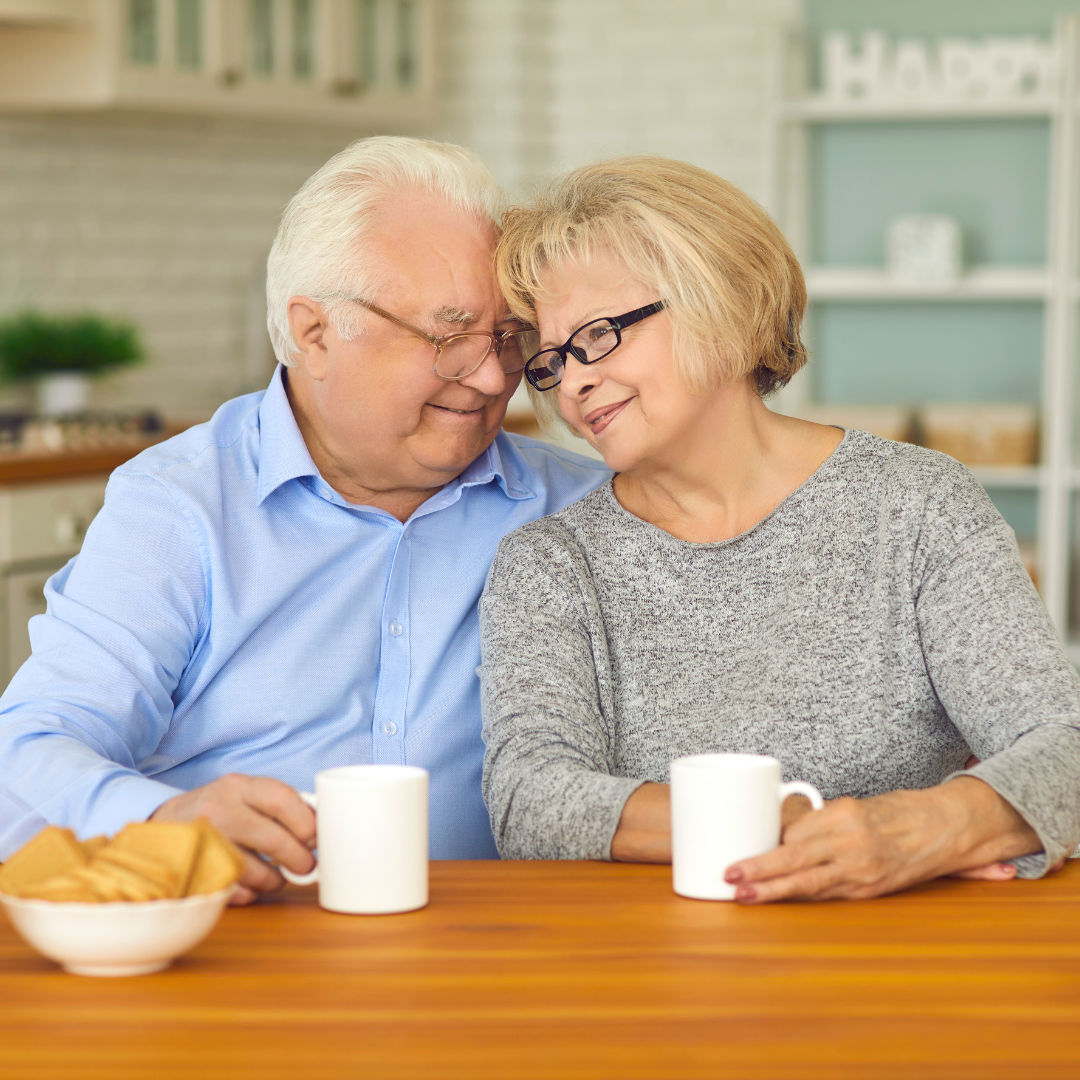 A man and a woman are sitting at a table with cups of coffee.