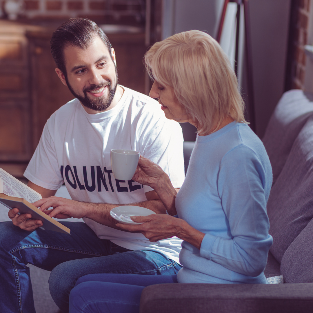 A man wearing a volunteer shirt sits on a couch with a woman
