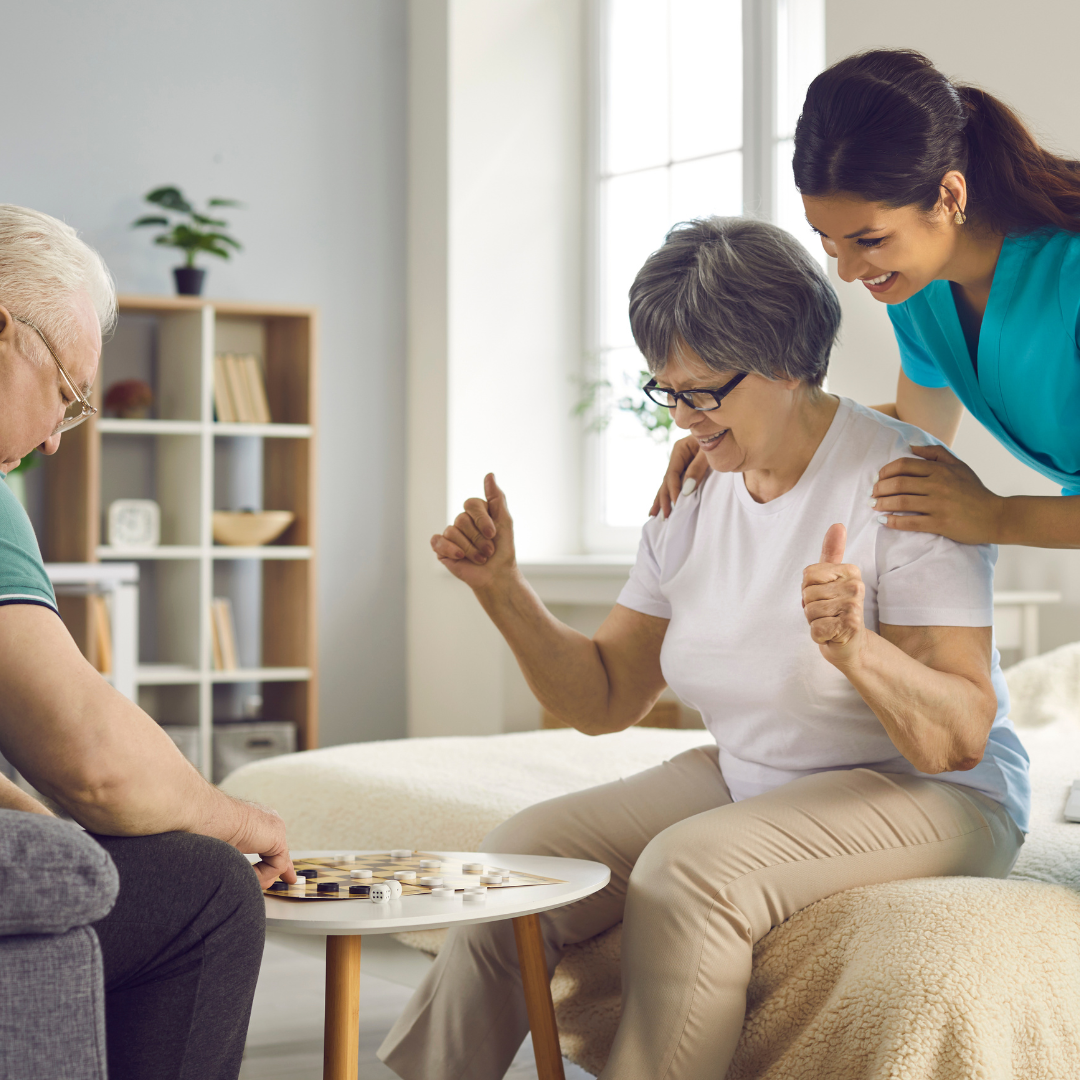 An elderly woman is giving a thumbs up while sitting on a couch.