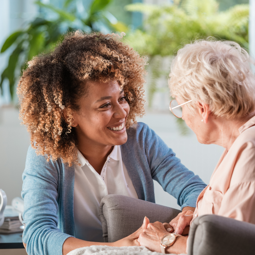 A woman is sitting on a couch talking to an older woman.