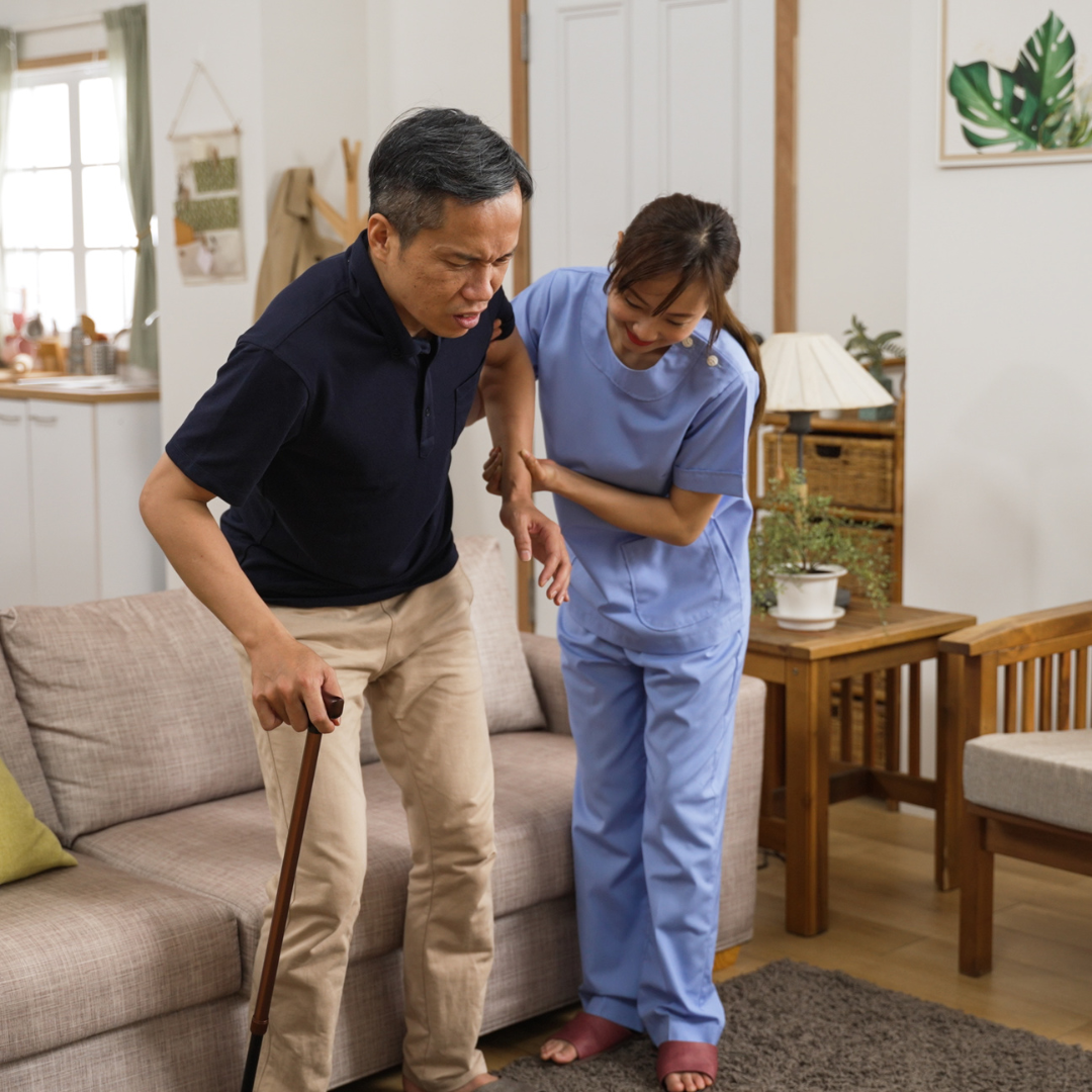 A man with a cane is being helped by a nurse in a living room.
