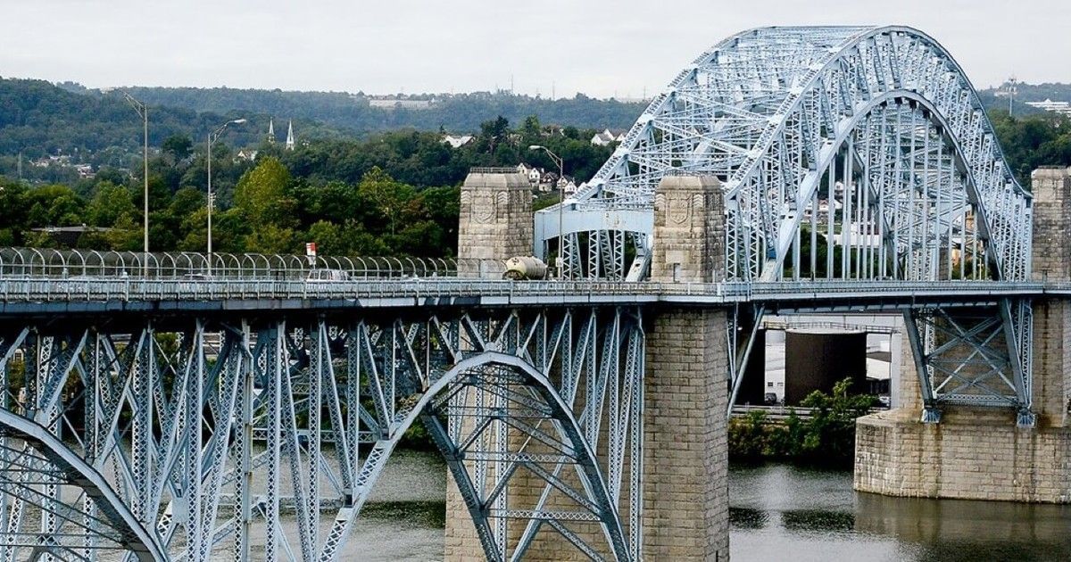 A bridge over a river with trees in the background.