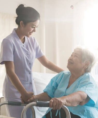 A nurse is talking to an elderly woman in a hospital bed.