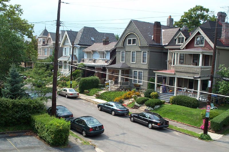 A row of houses with cars parked on the side of the road