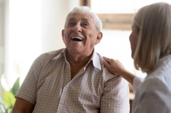 A woman is putting her hand on an older man 's shoulder.
