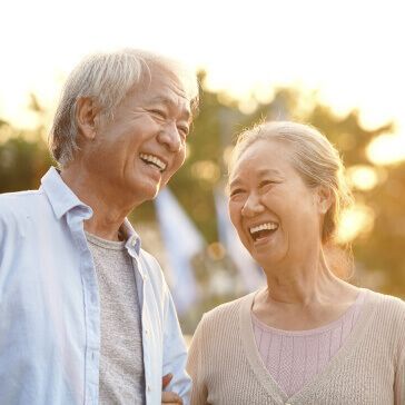 A man and a woman are laughing together while standing next to each other.