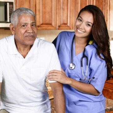 A nurse and an older man are posing for a picture in a kitchen