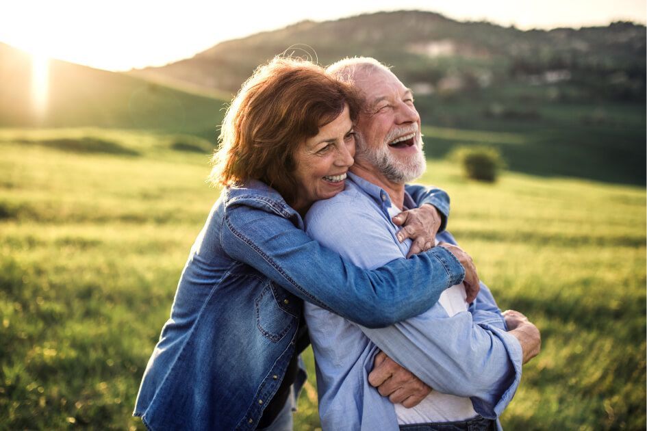 A man and a woman are hugging each other in a field.