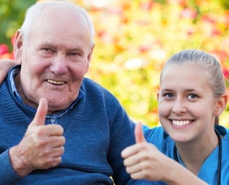 A nurse is giving an elderly man a thumbs up.