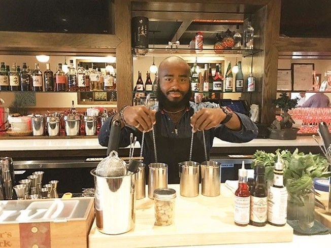 A man is standing behind a bar preparing a drink.