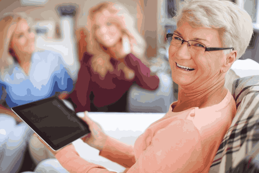 An elderly woman is sitting on a couch holding a tablet computer.