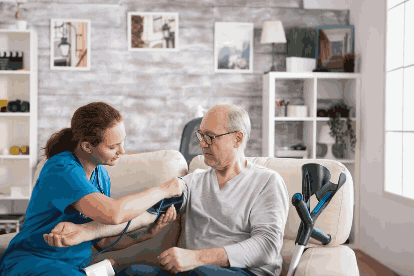 a caregiver is helping an elderly man check his basic health stats at home.a