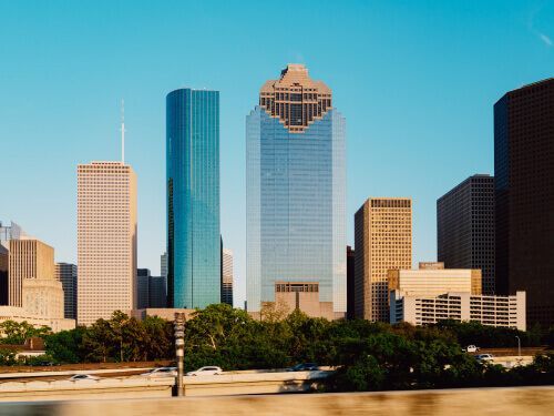 A city skyline with tall buildings and trees in the foreground
