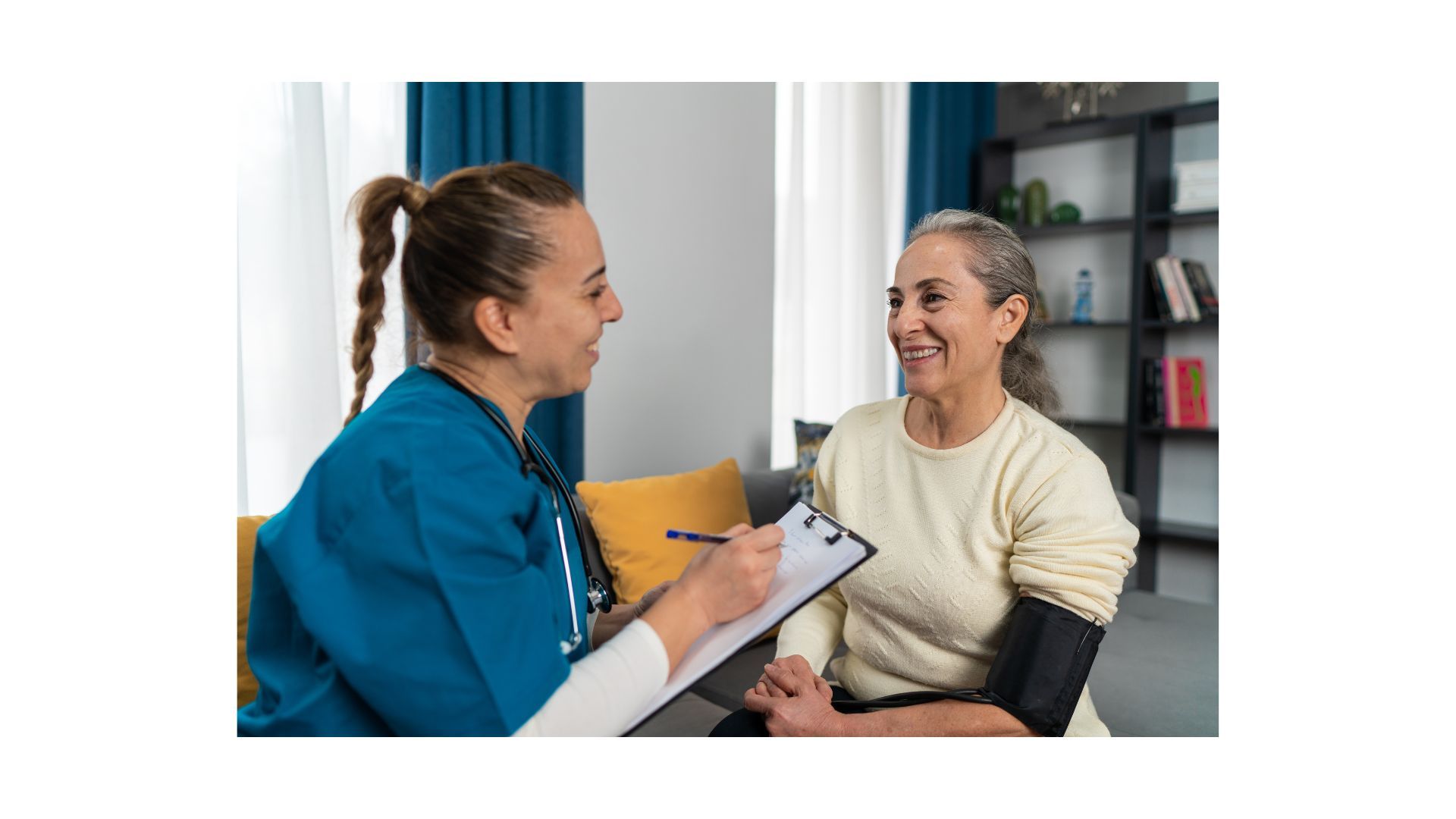 A nurse is talking to an elderly woman who is sitting on a couch.