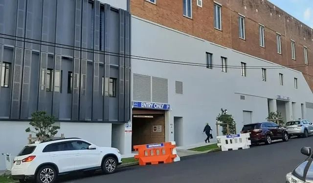 A White SUV Is Parked in Front of A Large Building — Action Physiotherapy in Cooks Hill, NSW