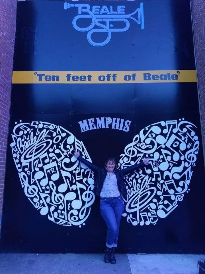 A Woman Stands in Front of A Sign that Says Ten Feet Off of Beale — Action Physiotherapy in Cooks Hill, NSW