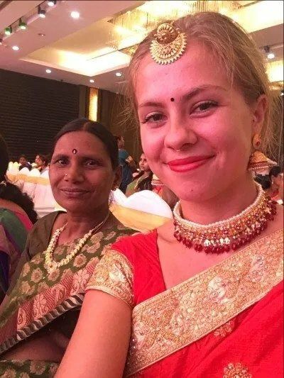 A Woman in A Red and Gold Dress Is Smiling for The Camera — Action Physiotherapy in Cooks Hill, NSW