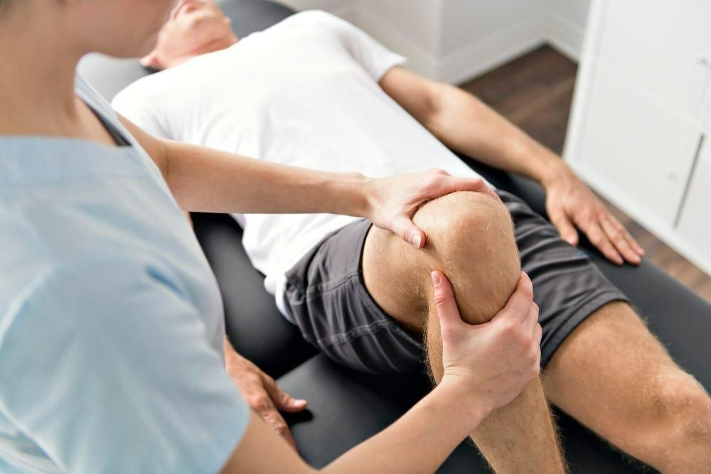 A Man Is Getting His Knee Examined by A Nurse — Action Physiotherapy in Cooks Hill, NSW