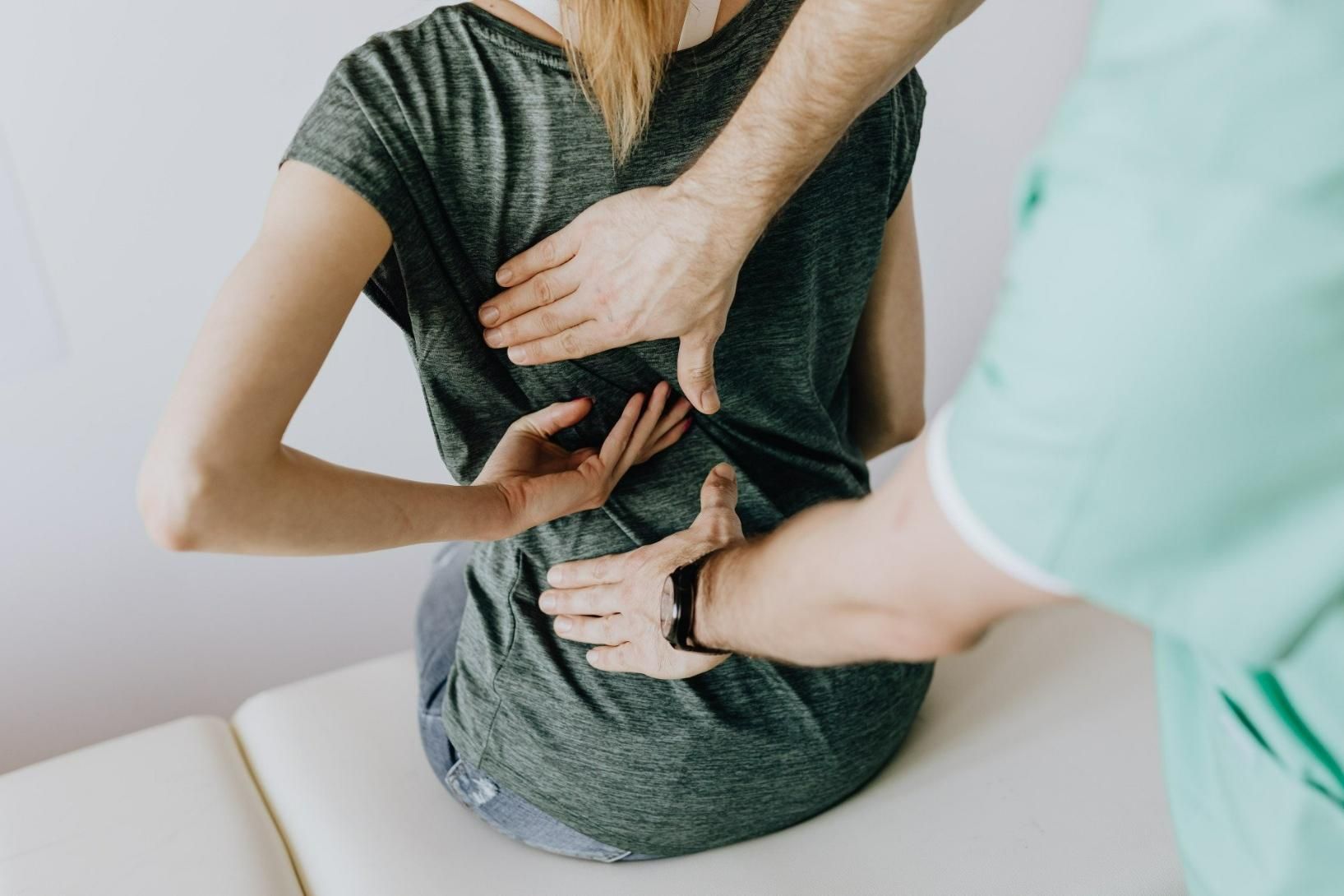 A Man Is Examining a Woman's Back on A Table — Action Physiotherapy in Cooks Hill, NSW