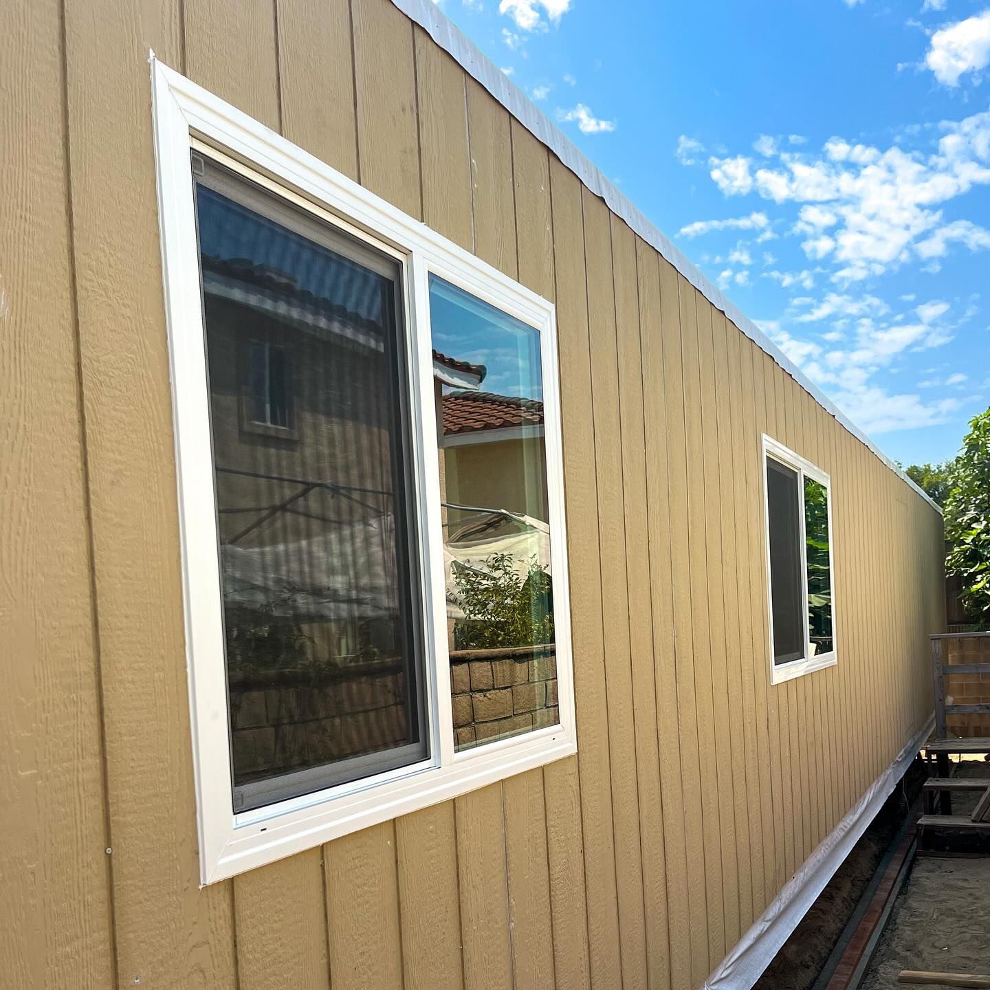 White-trimmed windows on a tan exterior wall of a building under a blue sky
