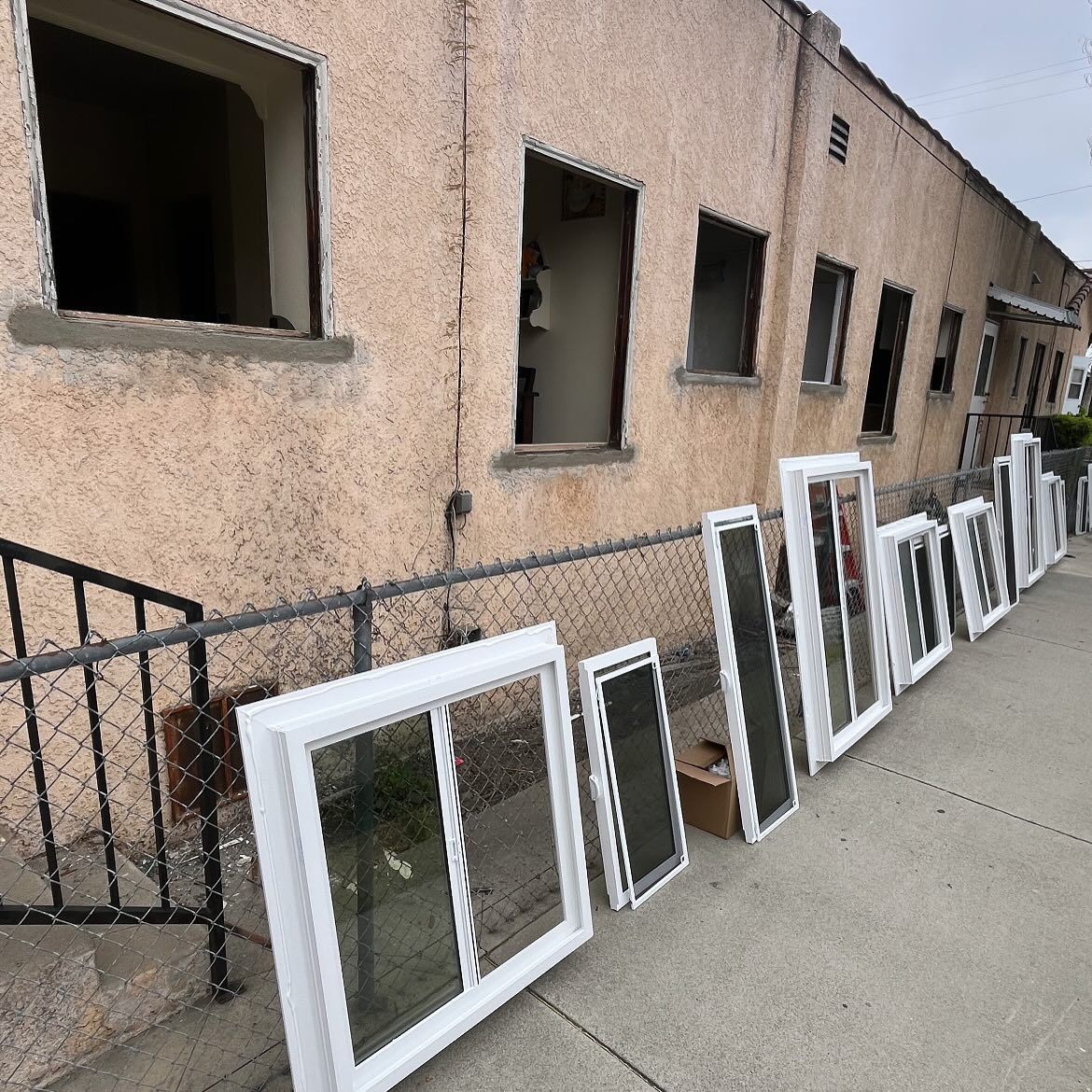 Windows and frames lined up against a beige building exterior on a sidewalk