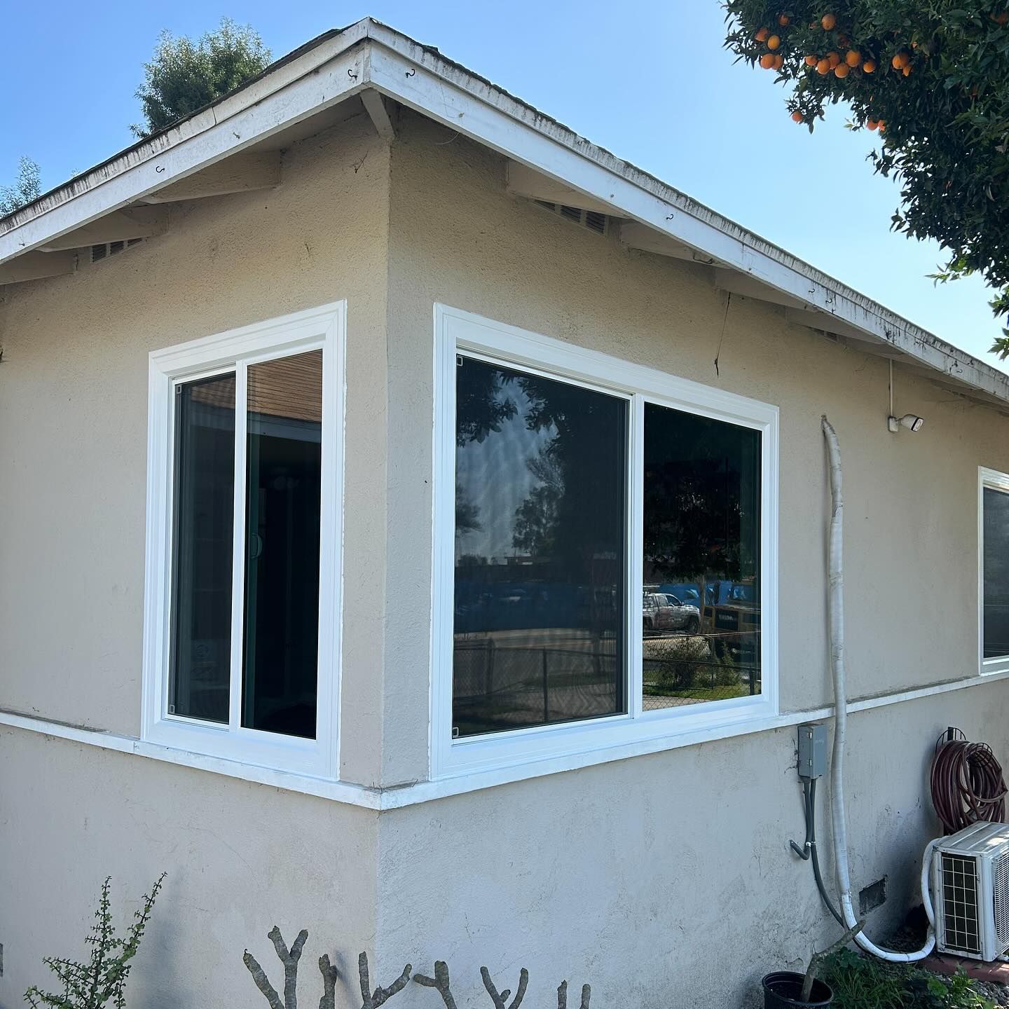 Beige house exterior with white-trimmed corner windows and a sloped roof, seen from the side.