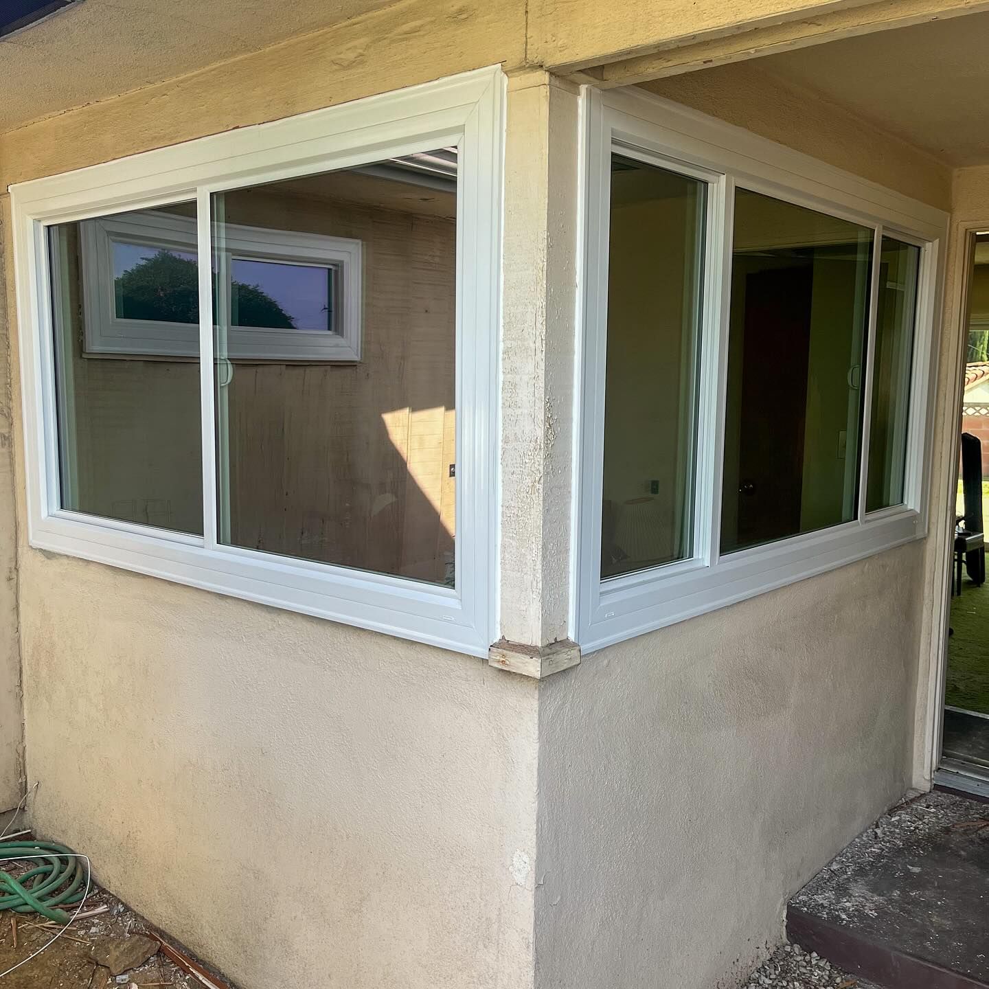 White-framed corner windows on a beige stucco house exterior