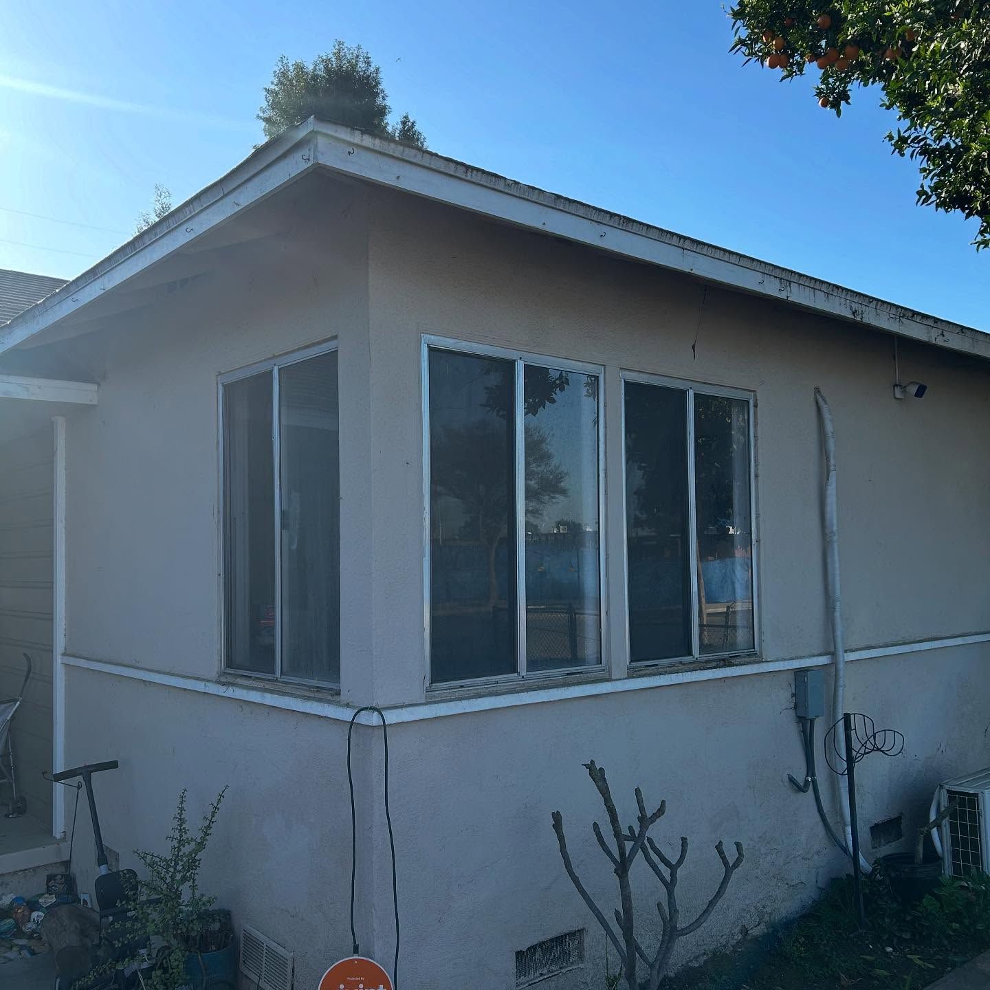 Small beige house exterior with white-trim windows under a blue sky