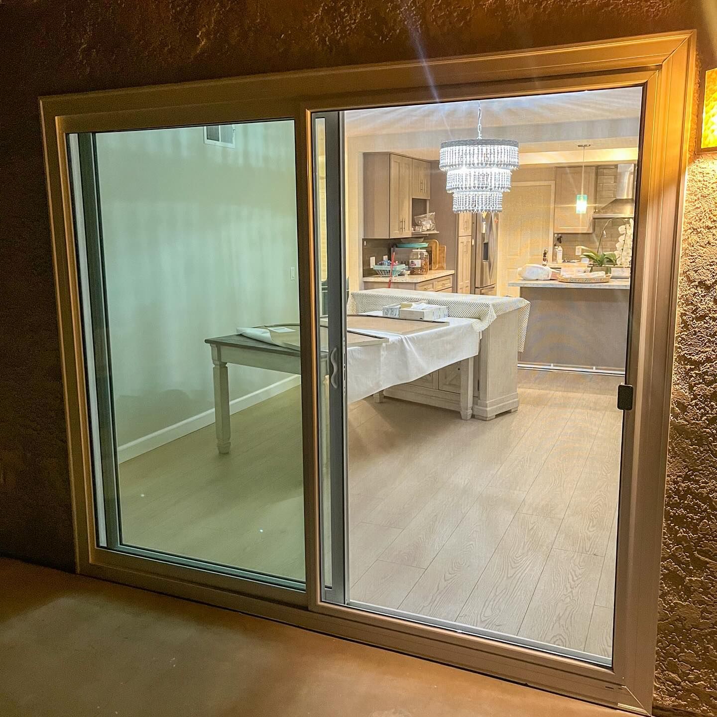 Sliding glass door with ornate gold frame, showing a dining room with a set table and chandelier inside