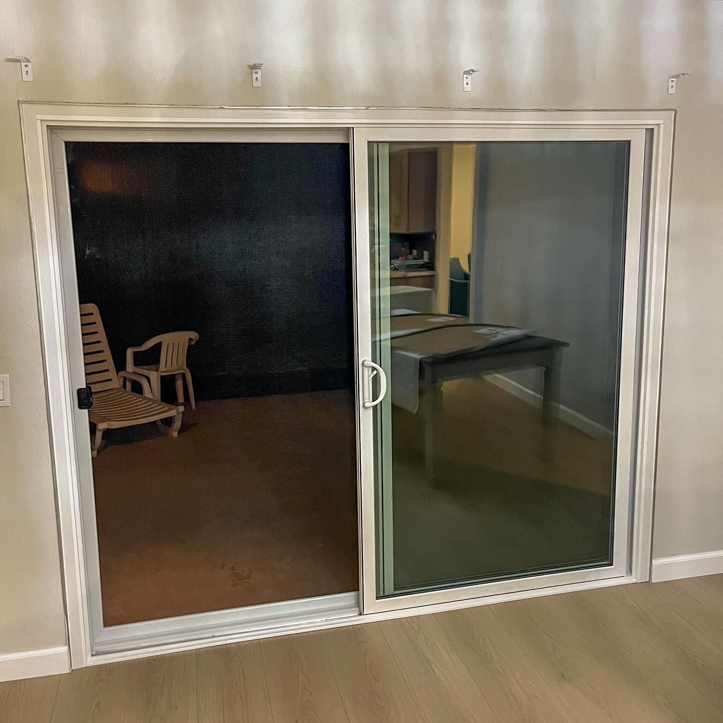 Sliding glass doors open to a dark patio with a chair and small table.