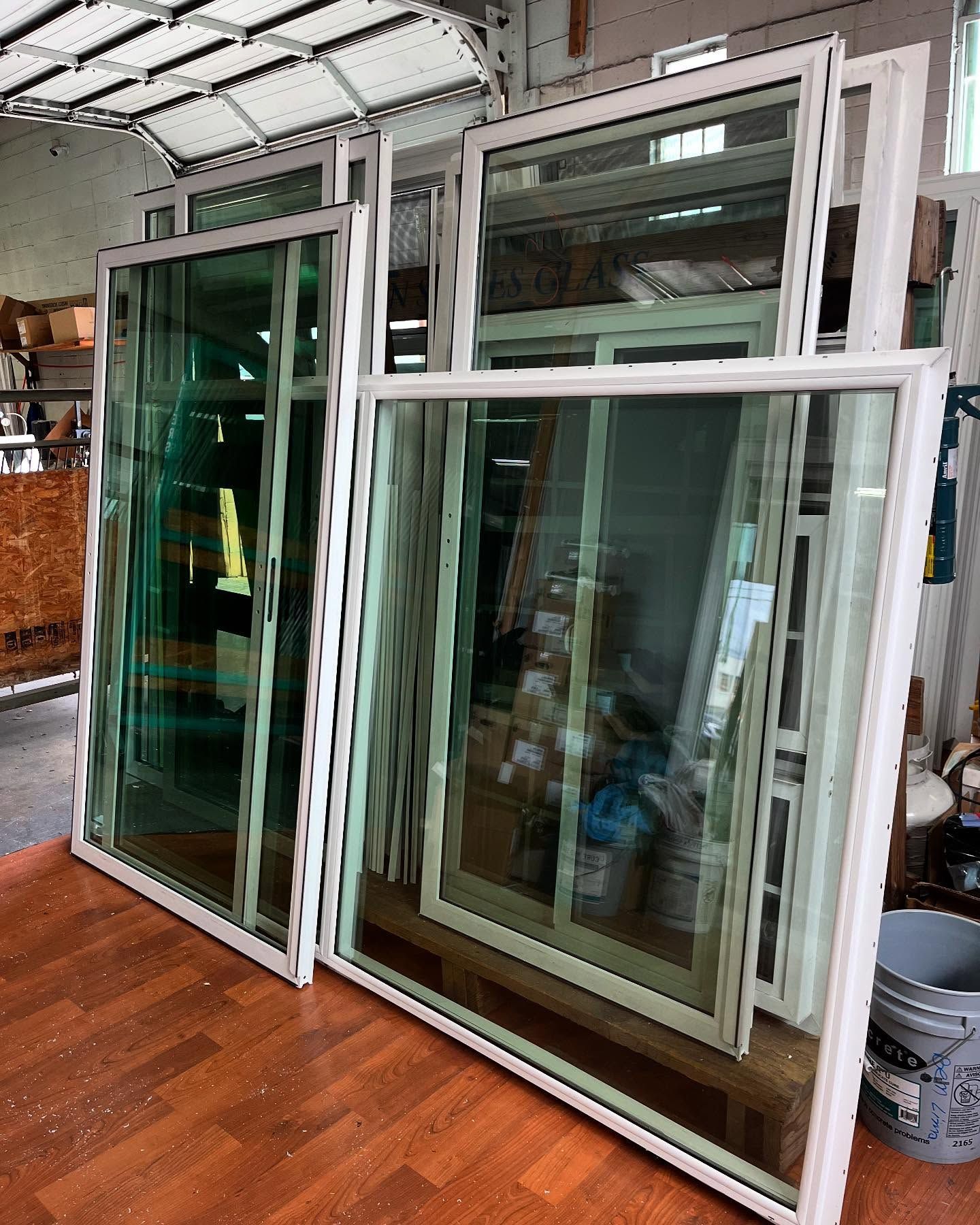 Stacked white-framed sliding windows in a workshop, with glass panes and a wood floor.