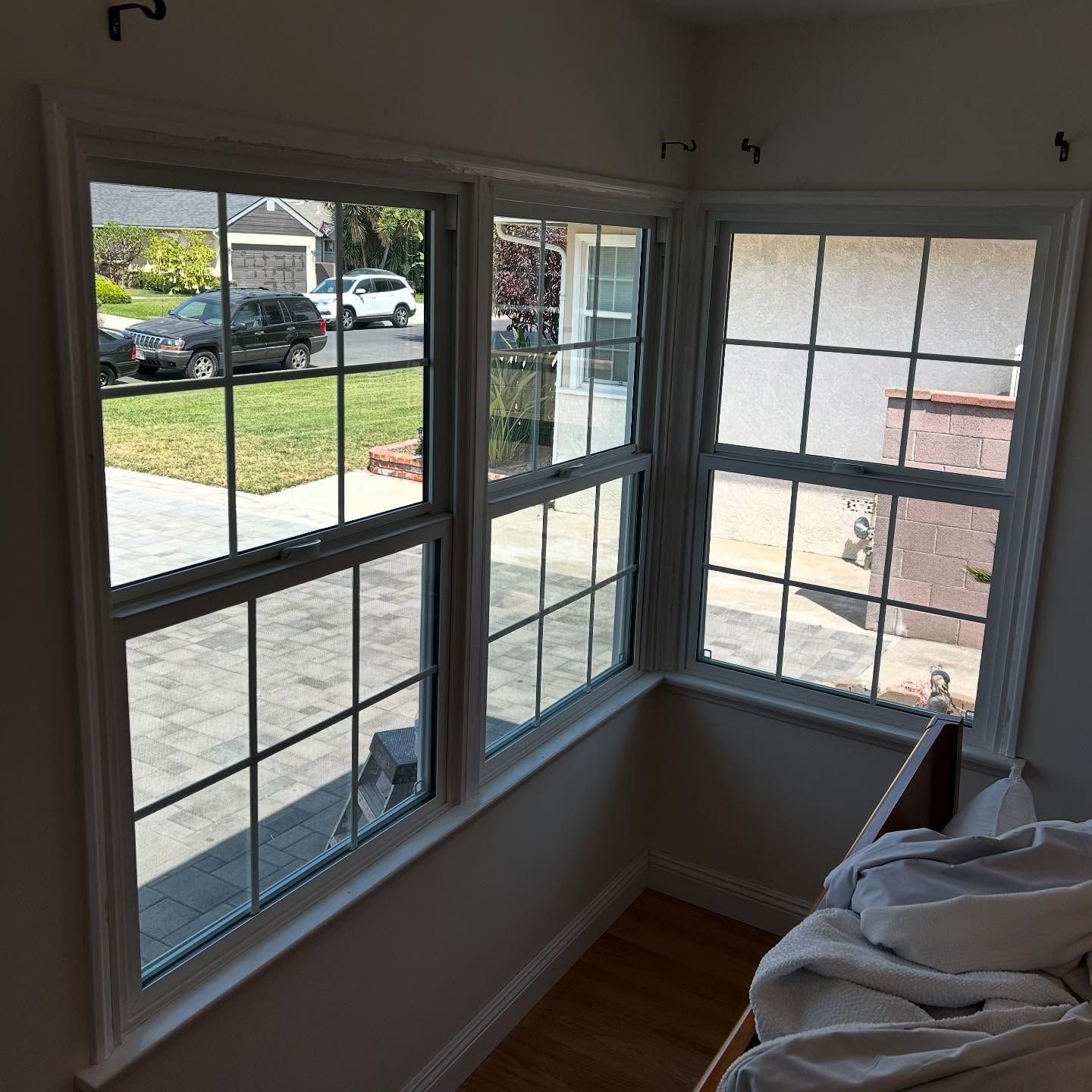 Bright bay window nook with white trim, wood floor, and a stack of folded fabric on the right