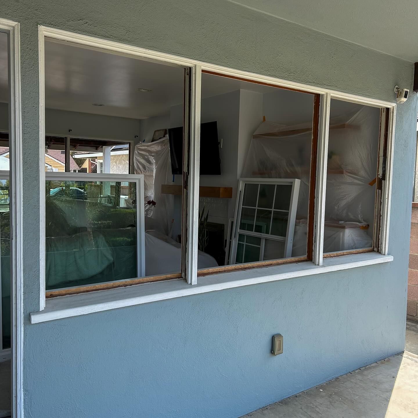 Blue stucco wall with four window openings, interior visible through broken or missing glass panes.