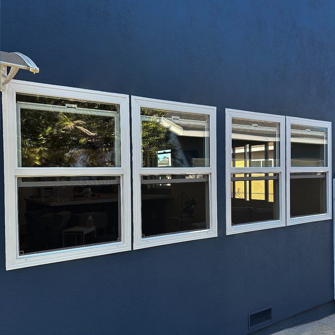 Blue building exterior with four white-framed windows reflecting the outdoors