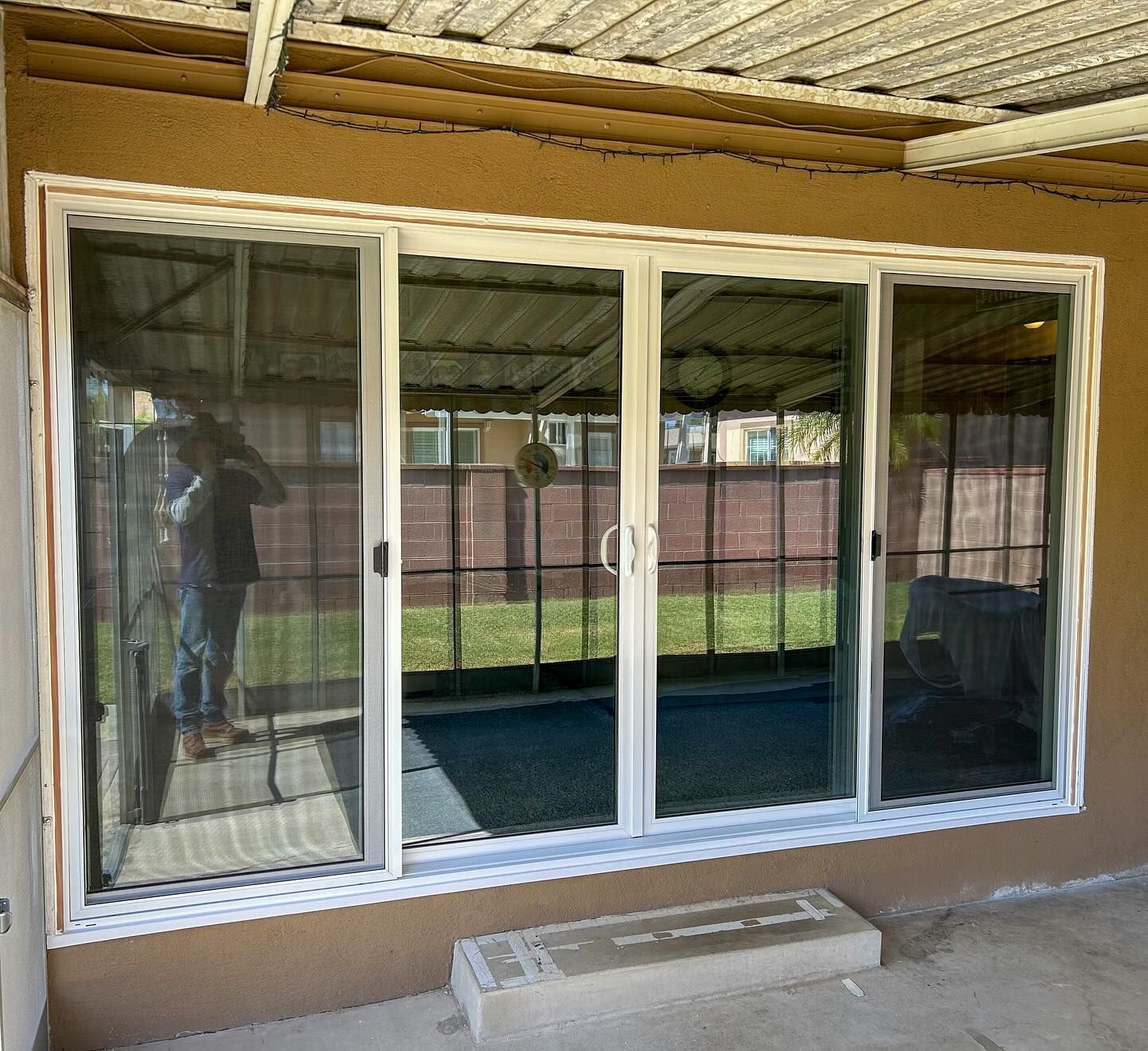 Large white sliding glass patio door set into a tan exterior wall under a covered porch.