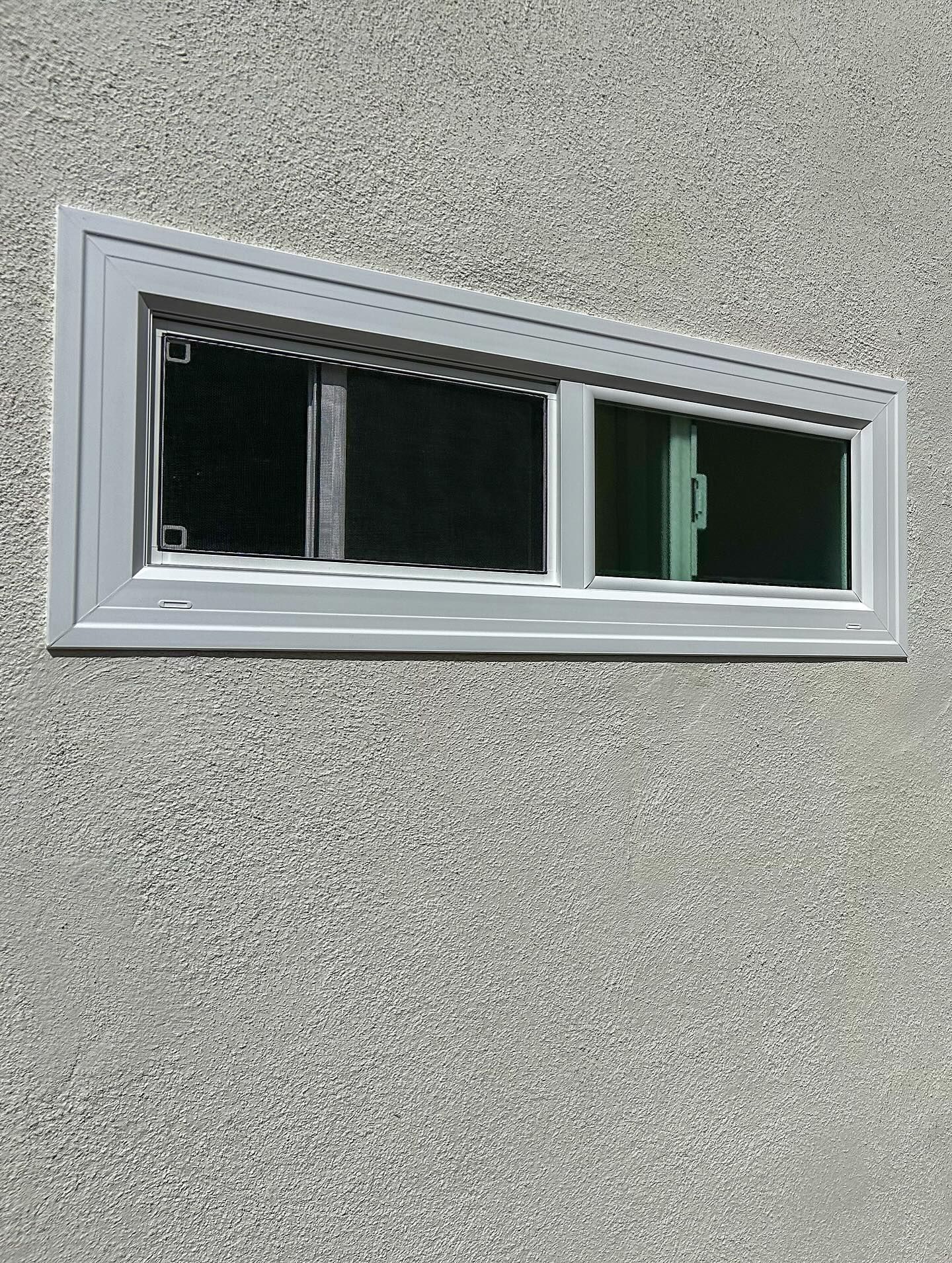 Small horizontal window with white frame set into a gray textured wall.
