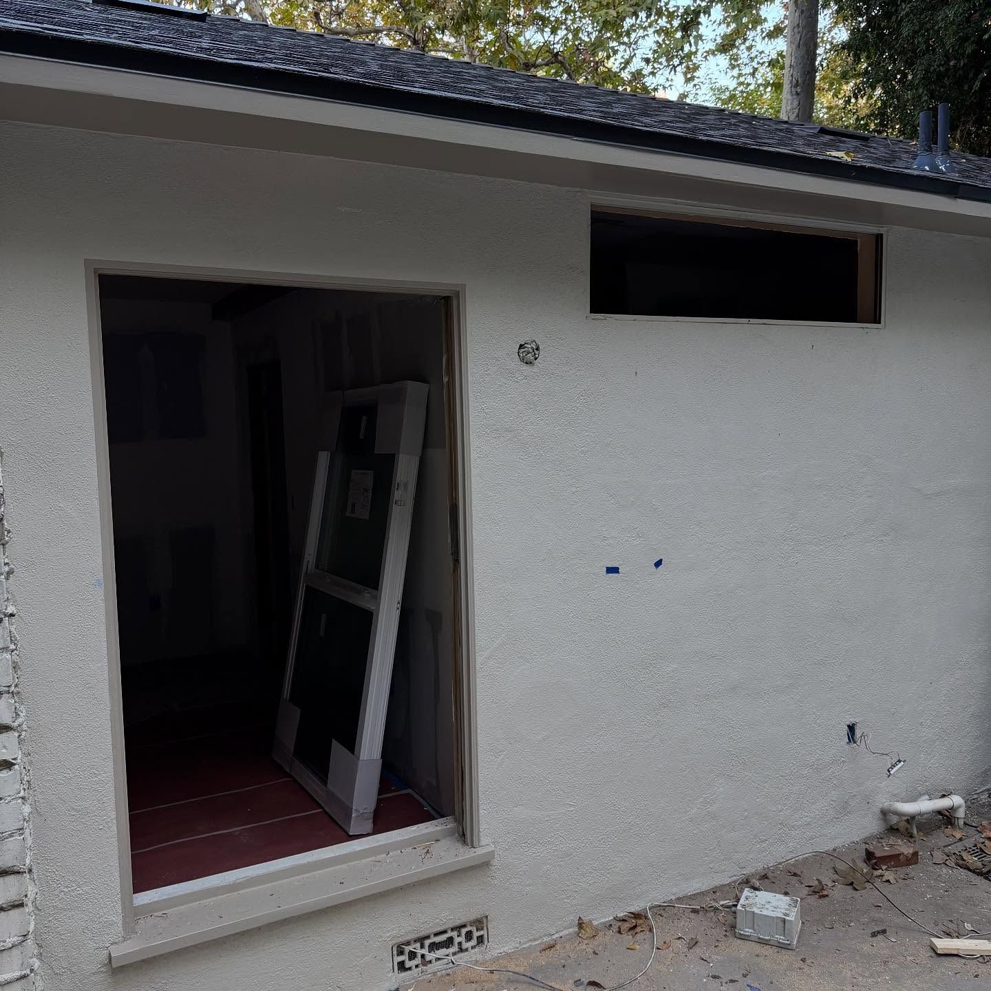 Exterior of a house with a wide open doorway and a small horizontal window above it