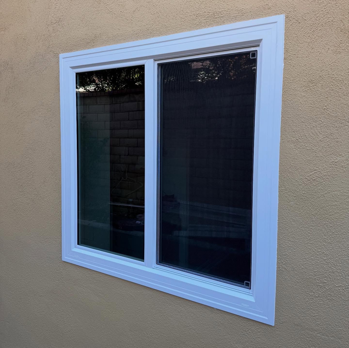 White-framed sliding window in a tan stucco wall