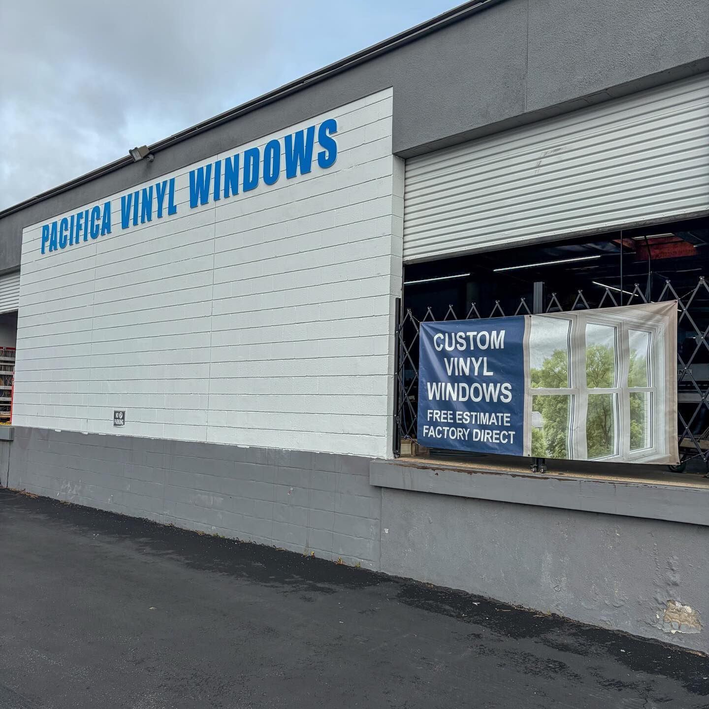 Pacific Vinyl Windows storefront with white exterior, blue sign, and window display banner