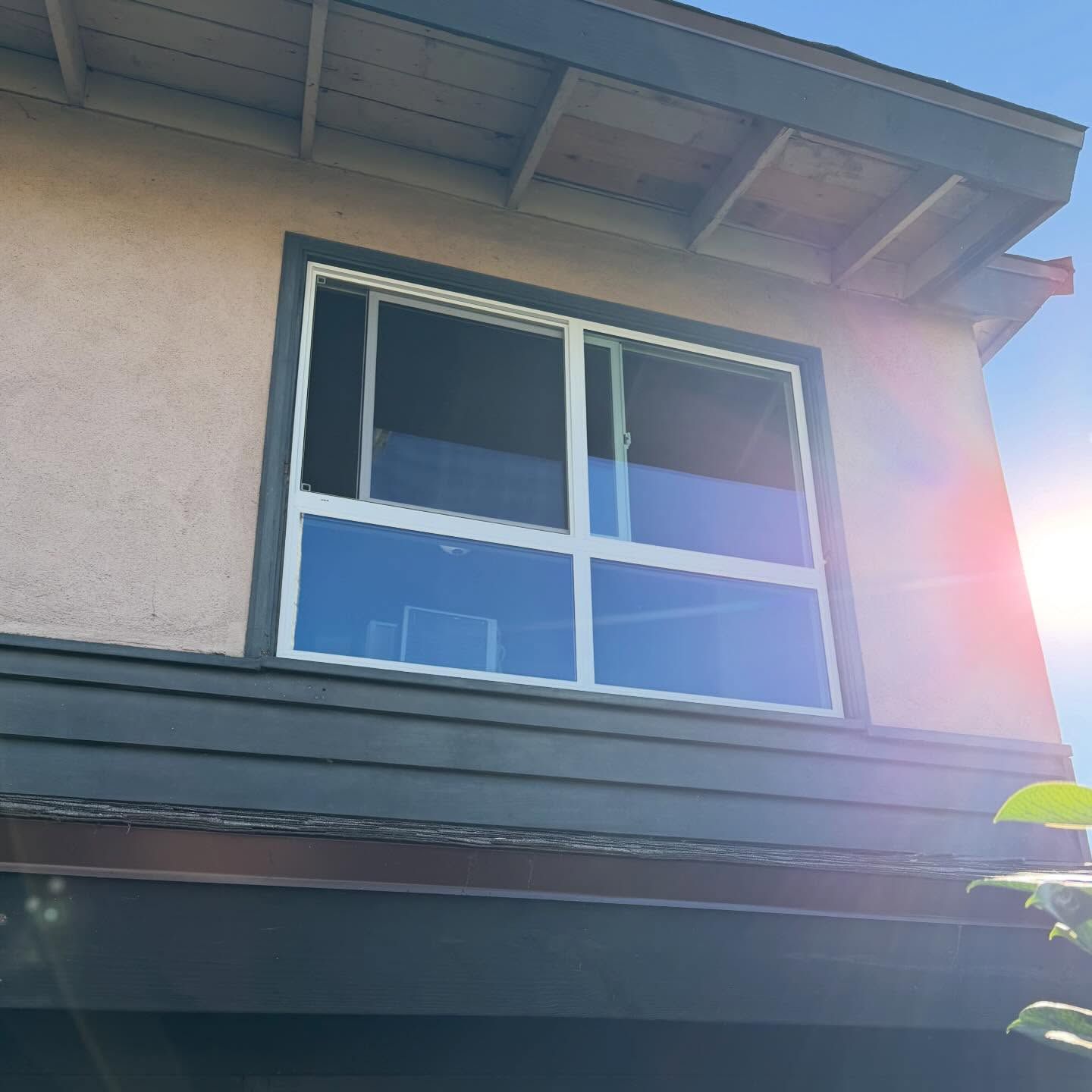 Exterior of a house with a second-story window and bright sun flare on the right side
