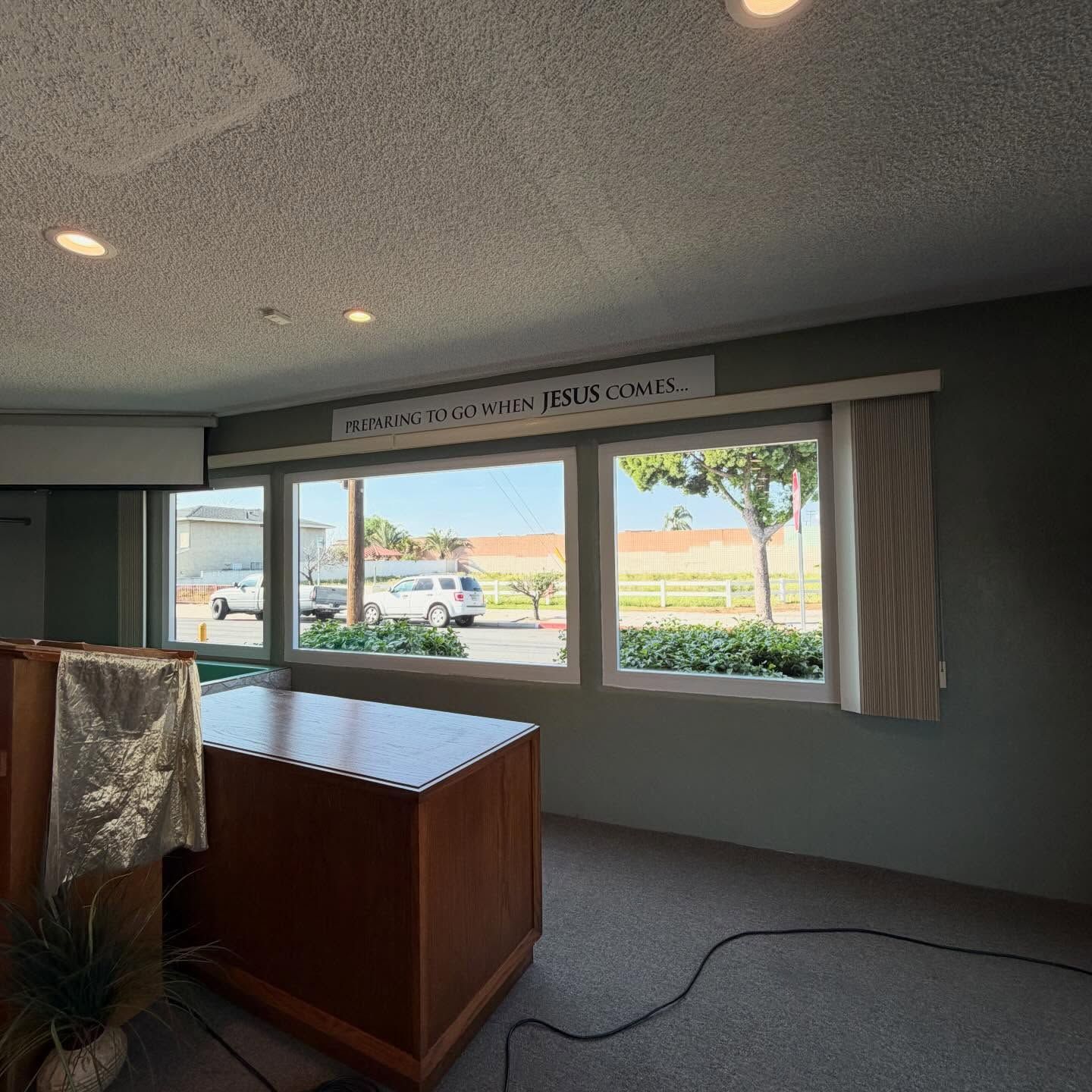 Empty room with large windows, a wooden lectern, and a sign above the windows.